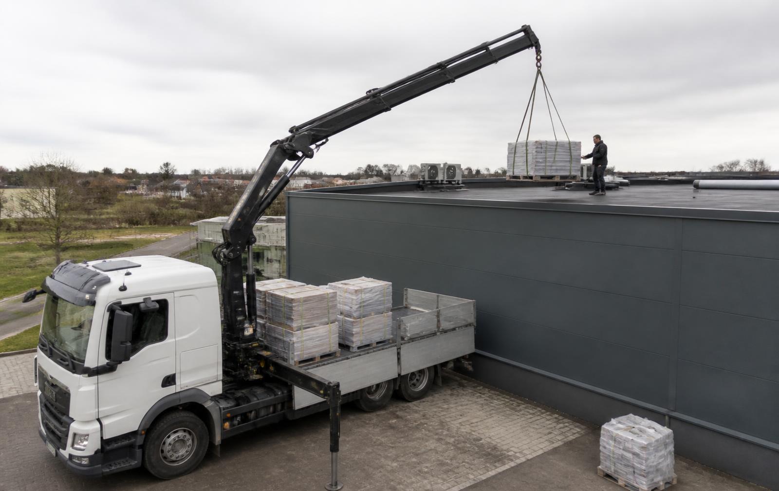 Kraanwagen van Bukro hijst materiaal op een plat dak